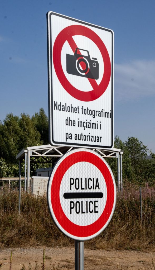 A no photography sign accompanied by a police warning sign, indicating restricted access to photography and authorized personnel only.